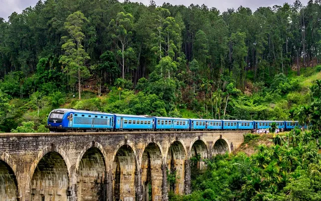 Tren azul atravesando un puente de piedra entre la vegetación de Sri Lanka